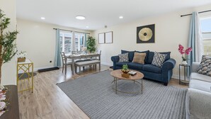 A modern living room with a sofa, coffee table, and dining area. - Duplx 6BD-3BH- 3 Parking (West New York)