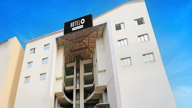 A modern hotel with a prominent entrance, a staircase leading to the lobby, and a sign indicating it is company-serviced. - Deluxe Bhagalpur Railway Junction (Bhāgalpur)