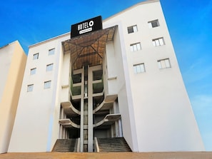 A modern hotel with a prominent entrance, a staircase leading to the lobby, and a sign indicating it is company-serviced. - Deluxe Bhagalpur Railway Junction (Bhāgalpur)