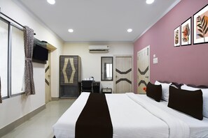 A hotel room with a bed, a desk, a chair, an air conditioning unit, and a television on the wall. - Super Collection O Kalighat (Kolkata)
