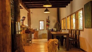 Un intérieur rustique avec des planchers en bois, une table à manger, des chaises et un chien.
