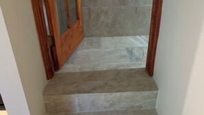 Una escalera con escalones de piedra y barandillas de madera, que conduce a una puerta con un panel de vidrio.
