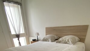 A bed with a patterned bedspread, a bedside lamp, and a nightstand with a radio. - Quiet house near the ocean (Saint-Hilaire-de-Riez)