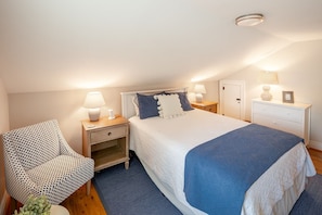 A bedroom with a bed, bedside tables, a chair, a wardrobe, and a ceiling light fixture. - Grace Creek Cottage, Minutes to St. Michaels, Pool, Dock (Bozman)