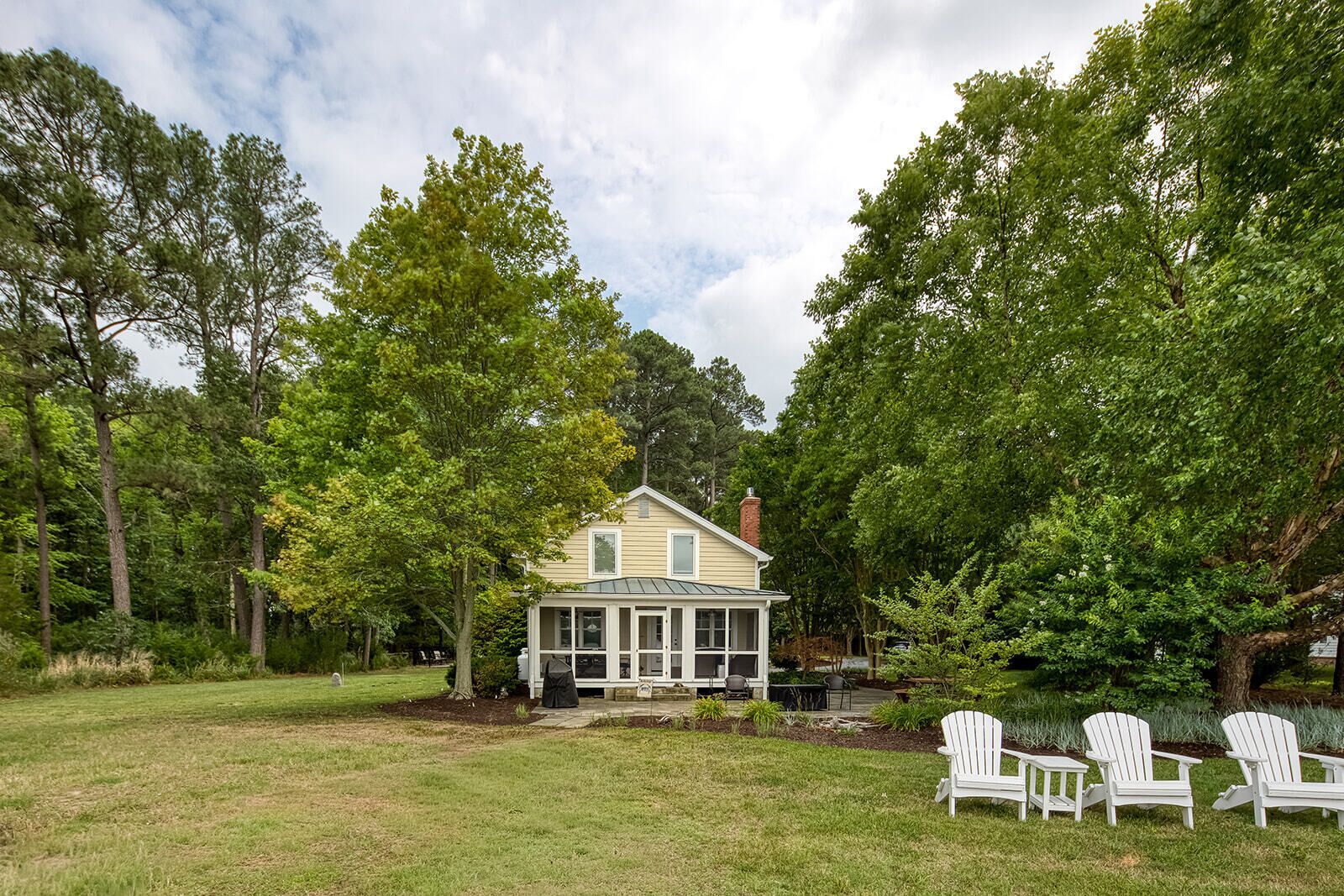 A house with a porch, surrounded by trees and a grassy yard.