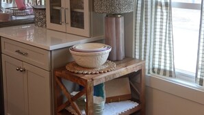 A kitchen with a wooden table, a bowl, a lamp, and a window with curtains. - Coastal cottage by the sea in Plymouth, MA with private beach access (Plymouth)