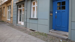 En rad med radhus med en blå dörr, en liten veranda och ett fönster med vit ram.
