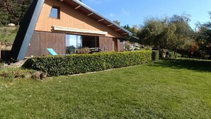 Una casa moderna con techo inclinado, ventanas amplias y un césped bien cuidado.