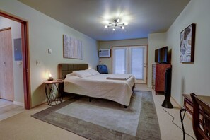 Une chambre à coucher comprenant un lit, une table de chevet, une lampe, un appareil de climatisation et un téléviseur.