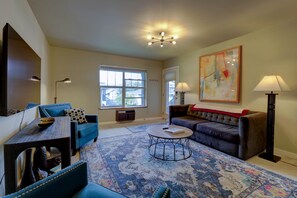 A living room with a blue sofa, a coffee table, a TV, and a large window. - Downtown Condo. 2 sept living areas. Free parking (Hood River)