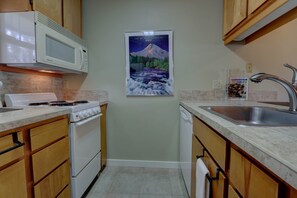 A compact kitchen with a stove, microwave, and sink. - Downtown Condo. 2 sept living areas. Free parking (Hood River)