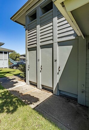 A building with three numbered garage doors, a concrete driveway, and a lawn. - Downtown Condo. 2 sept living areas. Free parking (Hood River)