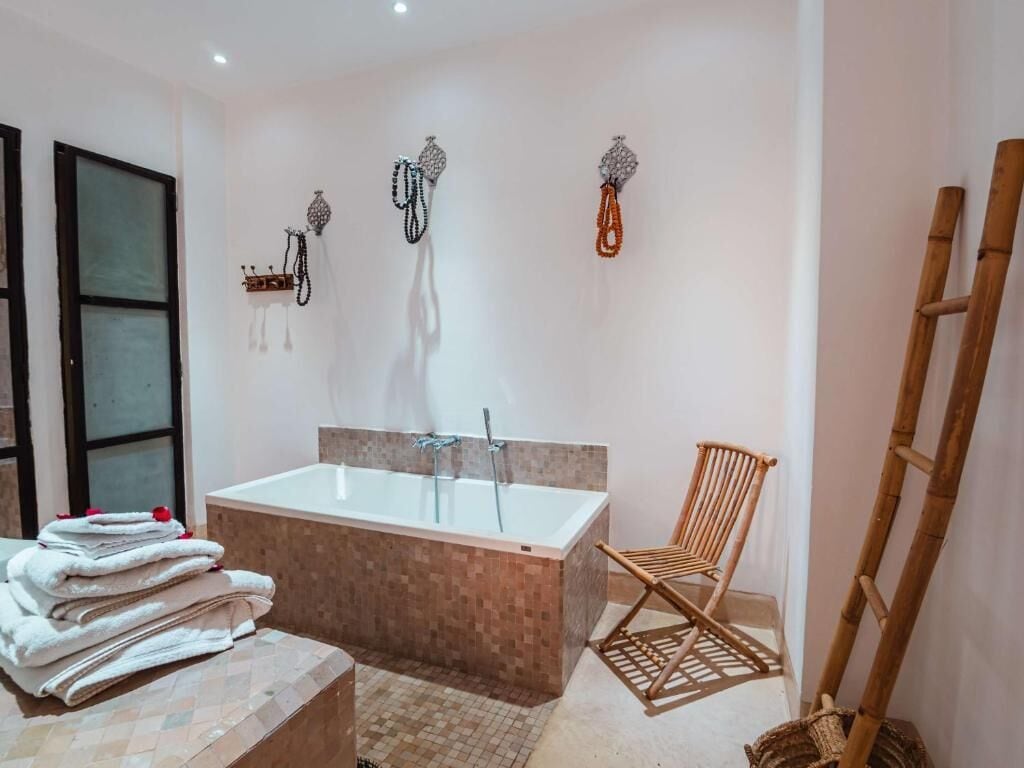A bathroom with a large bathtub, a chair, and a ladder.