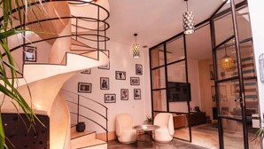 A modern interior with a spiral staircase, a seating area with two chairs, a small table, and a large glass door leading to another room. - Riad La source du Désert (Marrakech)