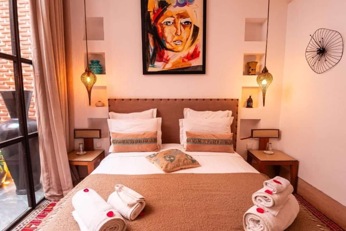 Een hotelkamer met een bed, twee nachtkastjes, een schilderij en een decoratief wandobject.