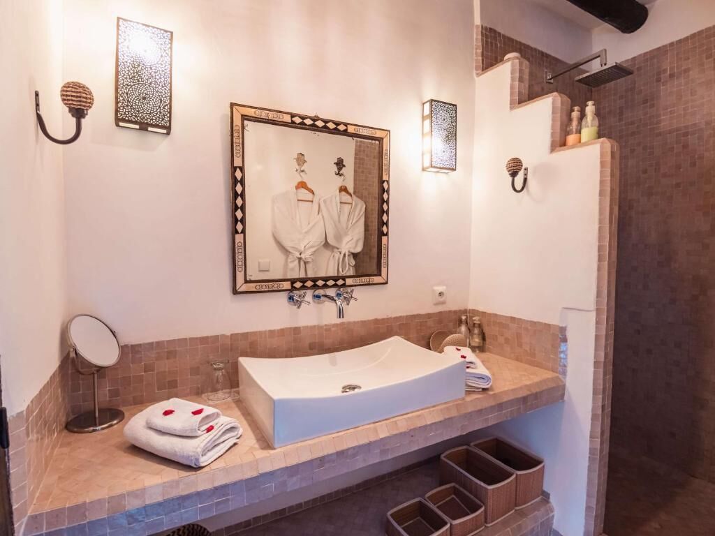 A bathroom with a large mirror, a sink, and a shower area.