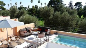 A rooftop pool area with lounge chairs, a sofa, and an umbrella. - Riad La source du Désert (Marrakech)
