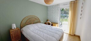 A bedroom with a bed, a bedside table, a mirror, and a view of the outdoors. - Cosy apartment Port de la Trinité-sur-Mer (La Trinité-sur-Mer)