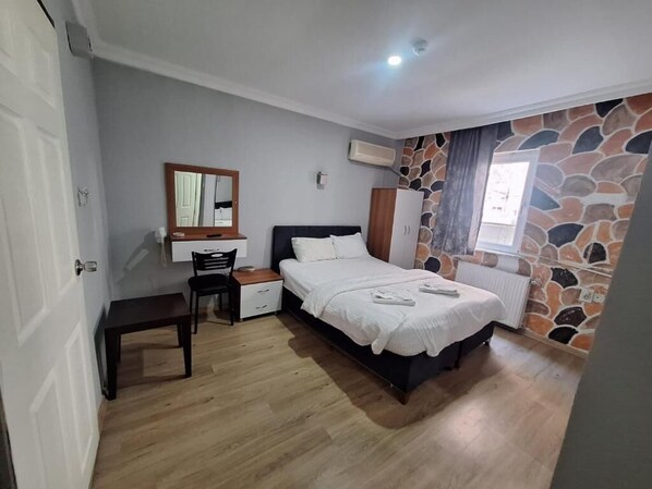 A bedroom with a bed, a chair, a desk, and a wardrobe. - mavikumsal otel (İstanbul)