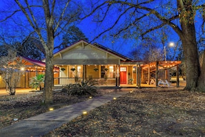 A two-story building with a porch, a covered area with string lights, and a pathway leading to the entrance.