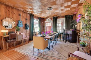 A wooden-paneled room with a dining table, chairs, a bar area, and a ceiling with a checkered pattern.