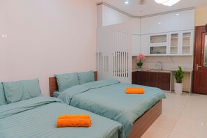 Un dormitorio con dos camas, una kitchenette pequeña y un baño.