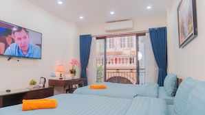 A hotel room with a television, a desk with a lamp, a bed with blue bedding, and a balcony with blue curtains. - IL DIVO Hotel & Spa Hanoi Old Quarter (Hanoi)
