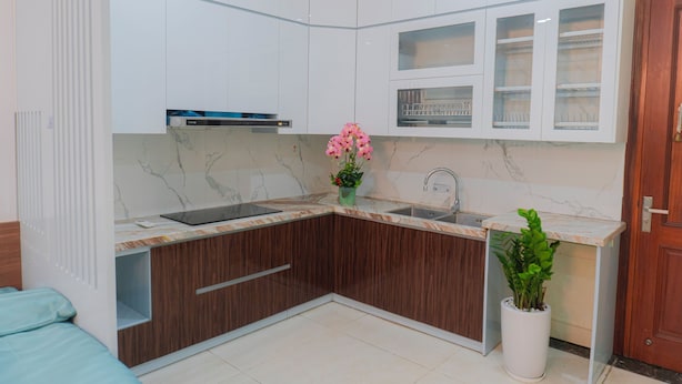 A modern kitchen with white cabinets, a marble countertop, a sink, and a potted plant. - IL DIVO Hotel & Spa Hanoi Old Quarter (Hanoi)