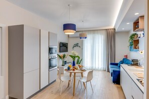 A modern kitchen with a dining area, a blue sofa, and a small island with a sink. - A Cozy Stay with Terrace in the Heart of Sorrento (Sorrento)