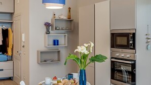 A modern kitchen with built-in appliances, a dining table with a vase of flowers, and a hanging light fixture. - A Cozy Stay with Terrace in the Heart of Sorrento (Sorrento)