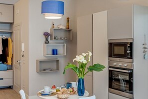 A modern kitchen with built-in appliances, a dining table with a vase of flowers, and a hanging light fixture. - A Cozy Stay with Terrace in the Heart of Sorrento (Sorrento)