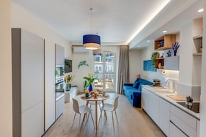 A modern kitchen with a dining area, a blue sofa, and a view of the city. - A Cozy Stay with Terrace in the Heart of Sorrento (Sorrento)