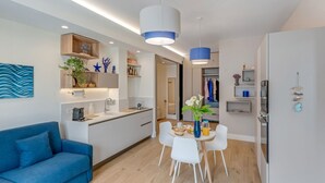 A modern kitchen with white cabinets, a blue sofa, and a dining area with a table and chairs. - A Cozy Stay with Terrace in the Heart of Sorrento (Sorrento)