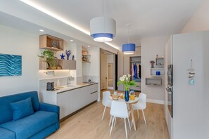 A modern kitchen with white cabinets, a blue sofa, and a dining area with a table and chairs. - A Cozy Stay with Terrace in the Heart of Sorrento (Sorrento)