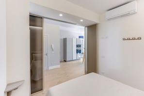 Ein modernes Hotelzimmer mit Bett, Schrank, Schreibtisch und einer Küchenzeile.