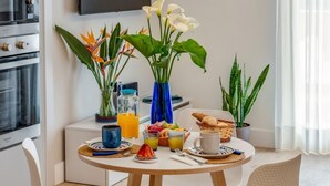 A dining table with breakfast items, a TV, and decorative plants. - A Cozy Stay with Terrace in the Heart of Sorrento (Sorrento)