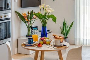 A dining table with breakfast items, a TV, and decorative plants. - A Cozy Stay with Terrace in the Heart of Sorrento (Sorrento)