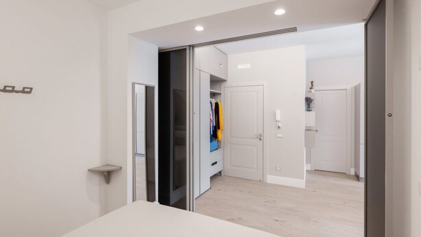 A modern bedroom with a bed, a closet, and a bathroom visible through an open door. - A Cozy Stay with Terrace in the Heart of Sorrento (Sorrento)