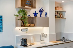A modern kitchen with white countertops, a sink, a coffee machine, and decorative items like a starfish and a plant. - A Cozy Stay with Terrace in the Heart of Sorrento (Sorrento)