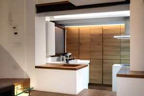Eine moderne Küche mit einer Wandpaneele aus Holz, einem eingebauten Backofen und einer Kücheninsel mit Glasfronten.