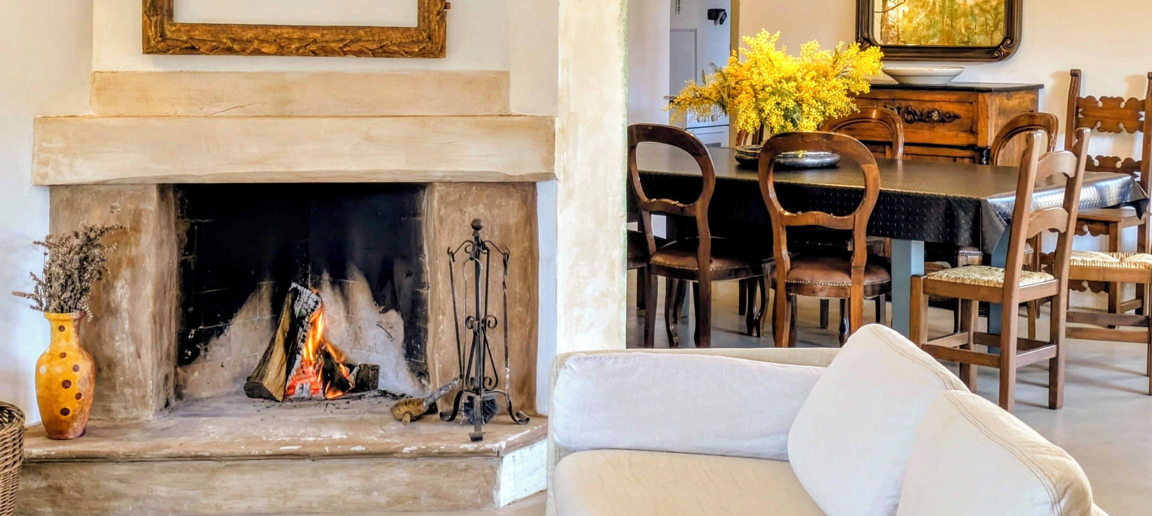 A living room with a fireplace, a dining table with chairs, and a sofa.