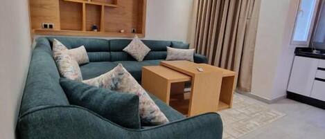 Un salon moderne avec un canapé de couleur turquoise, des étagères en bois et une petite table en bois.