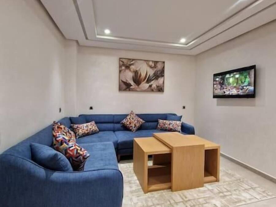 Ein modernes Wohnzimmer mit einem blauen Modulsessel, einem Holztisch und einem flachbildfernseher, der an der Wand montiert ist.