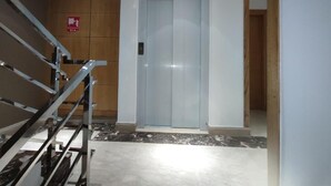 Ein moderner Aufzug mit Metallhandlauf und einer hellen Wand.