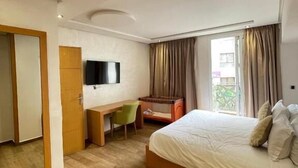 Ein Schlafzimmer mit Bett, Schreibtisch, Stuhl, Fernseher und Kleiderschrank.