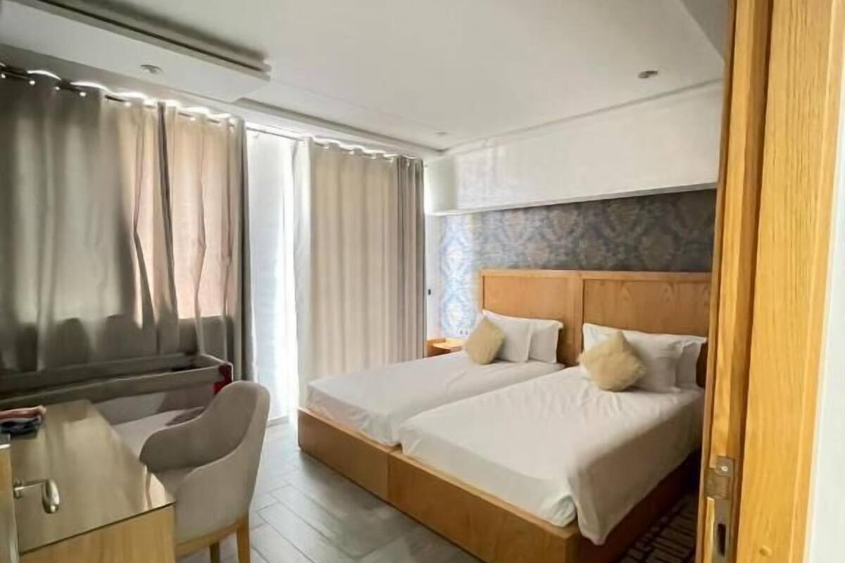 A hotel room with a bed, desk, chair, and a view of the outside.