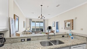A kitchen with granite countertops, a double sink, and a chandelier. - The Inn #412 ~ Top Floor ~ Amazing Views (Dauphin Island)
