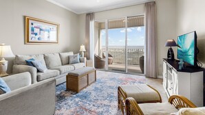 A hotel room with a balcony, a sofa, a TV, and a painting. - The Inn #412 ~ Top Floor ~ Amazing Views (Dauphin Island)