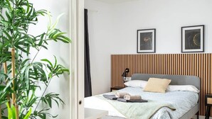 Une chambre à coucher avec un lit, des tables de chevet, une lampe et deux tableaux encadrés accrochés au mur.