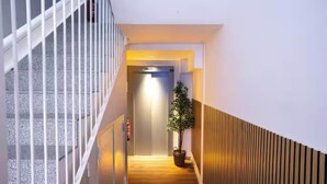 Un couloir d’hôtel moderne avec un plancher en bois, une rambarde blanche et une plante en pot.